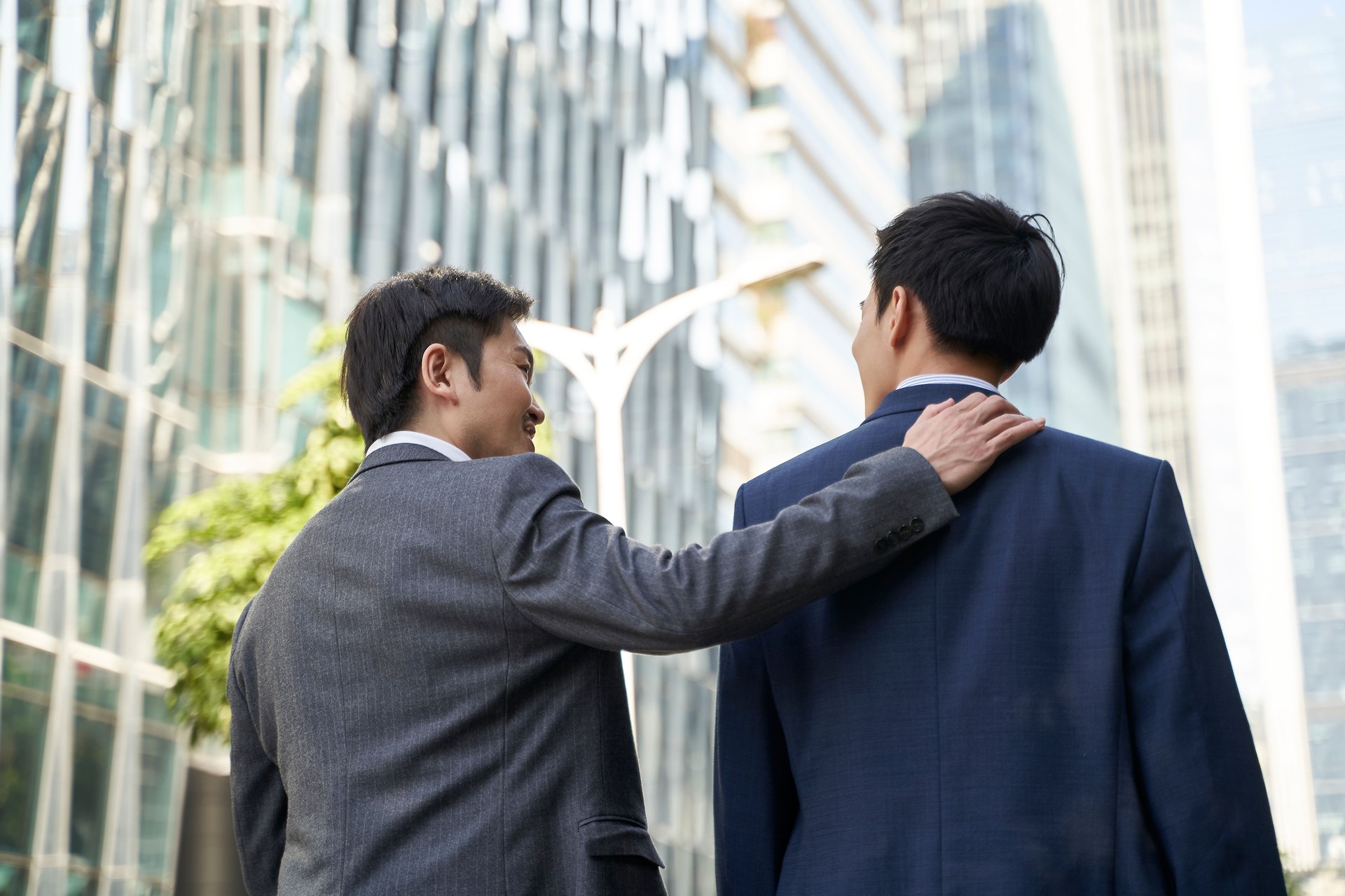 two asian business people walking talking on street