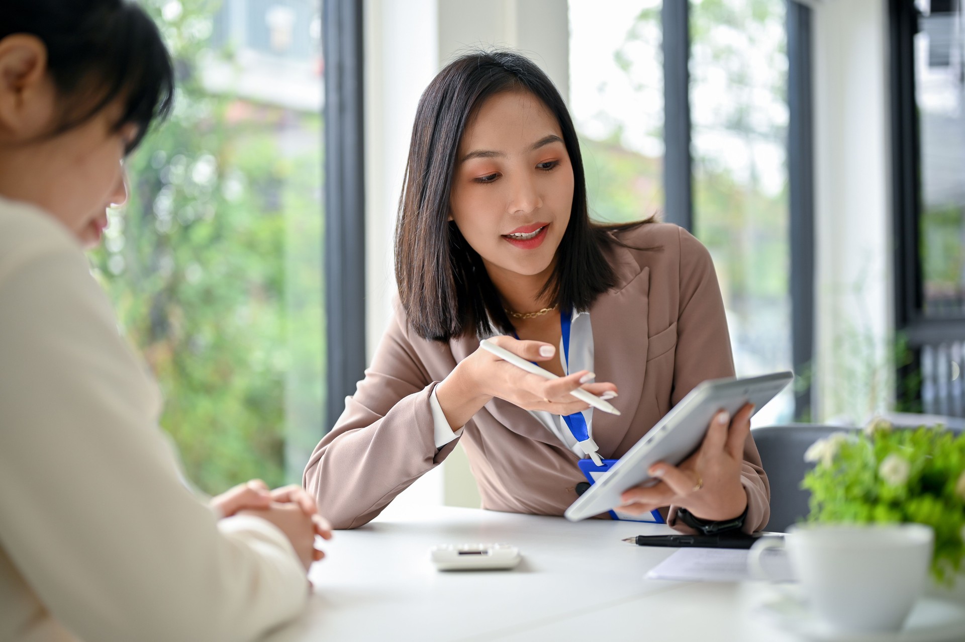 Focused Asian businesswoman using tablet, discussing work and working with her colleague
