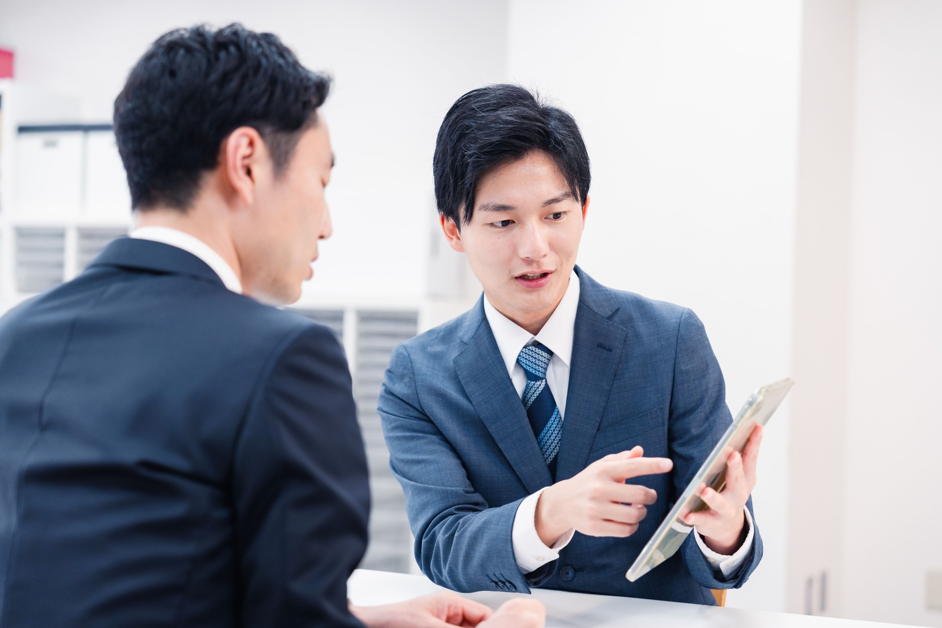 Businessman using a tablet terminal to explain at the counter.